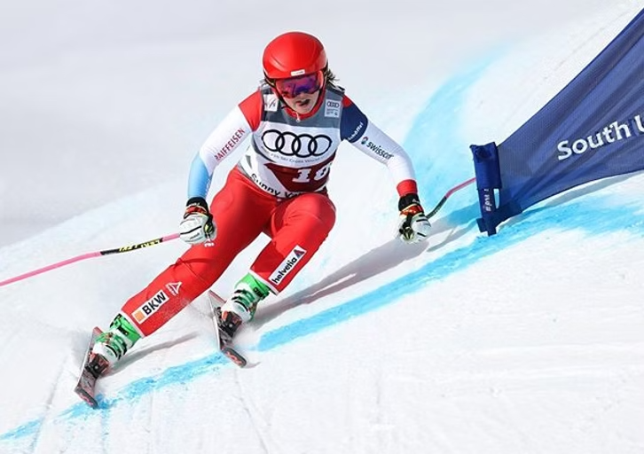 Sixtine Cousin sur les skis en actions dans un virage au couleur de la suisse avec un dossard jeux olympiques